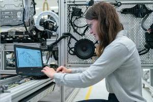 年轻的女性系统工程师在实验室设备周围的笔记本电脑上工作